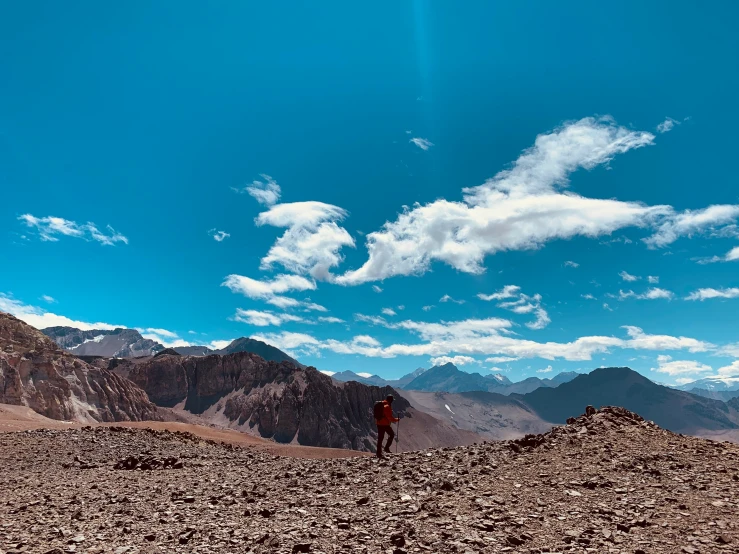 a person standing on top of a rocky hill with mountains in the background