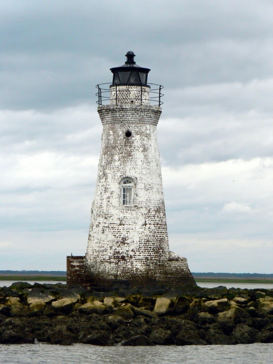 a lighthouse with a roof and railing sitting on a rock