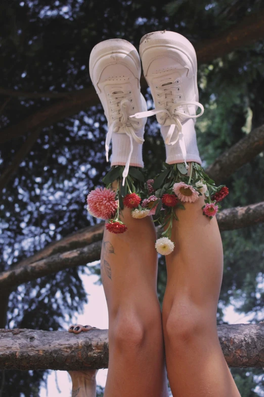 the legs of a woman wearing tennis shoes are decorated with flowers