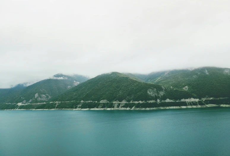 mountain and body of water under cloudy skies