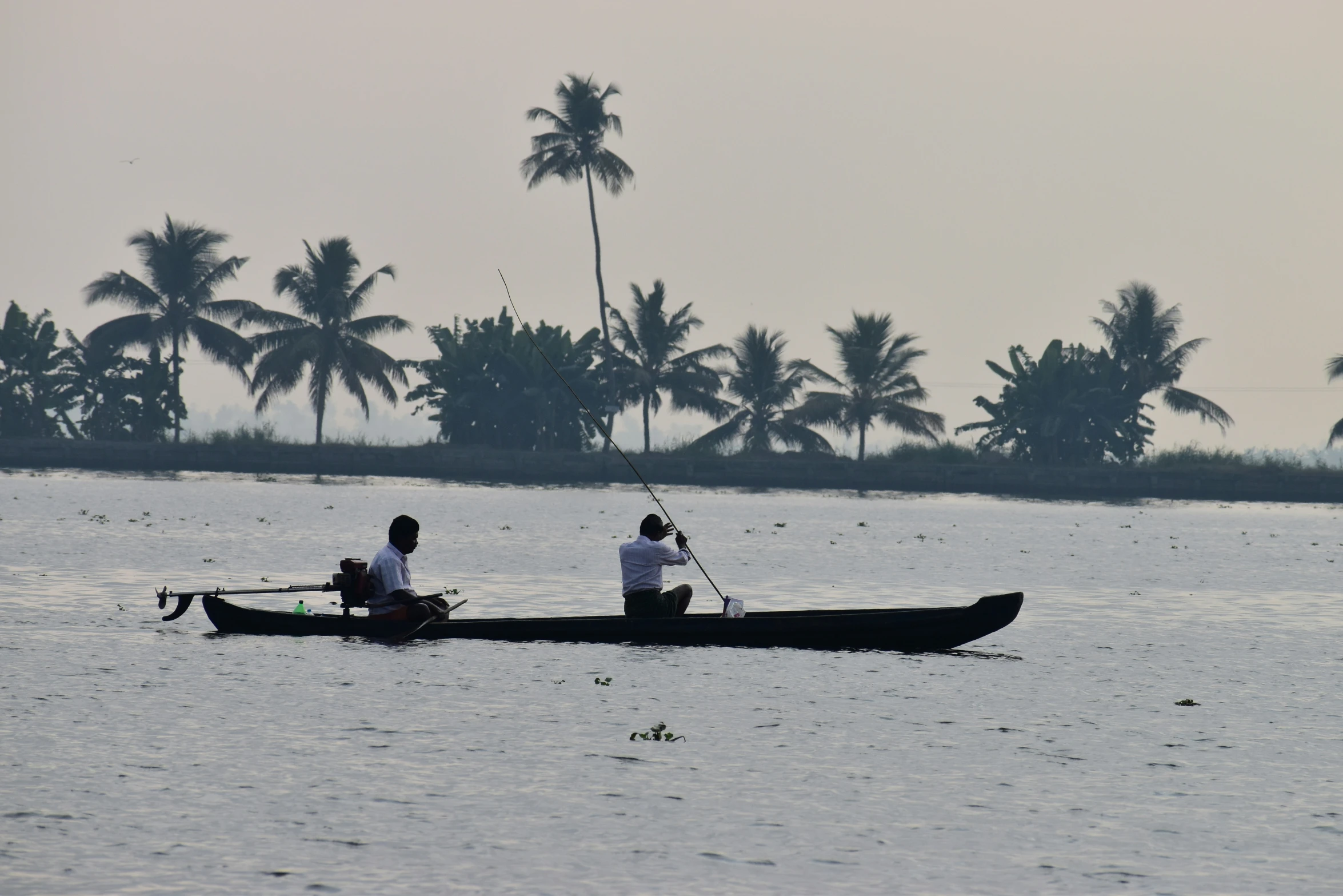 two people in a long boat paddling down the river