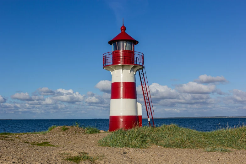 a very tall red and white lighthouse on the shore