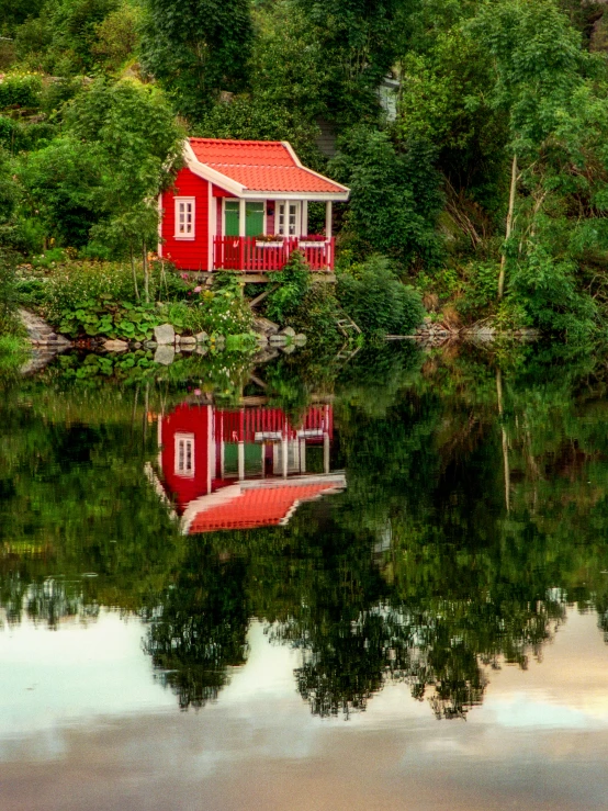 a house sitting on top of a small lake next to trees