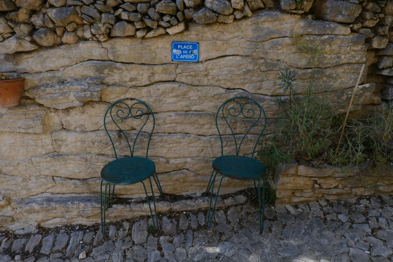 two green chairs near a wall with flowers