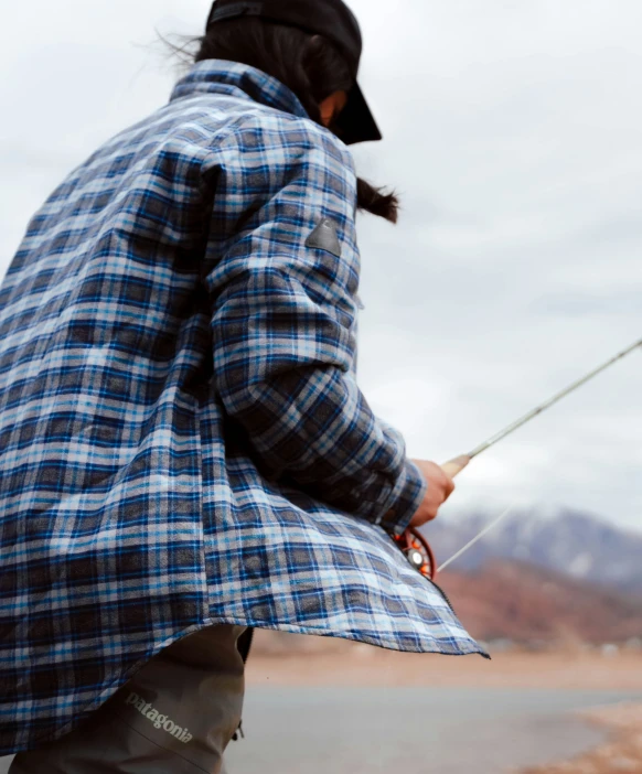 a person holding a fishing line next to some mountains