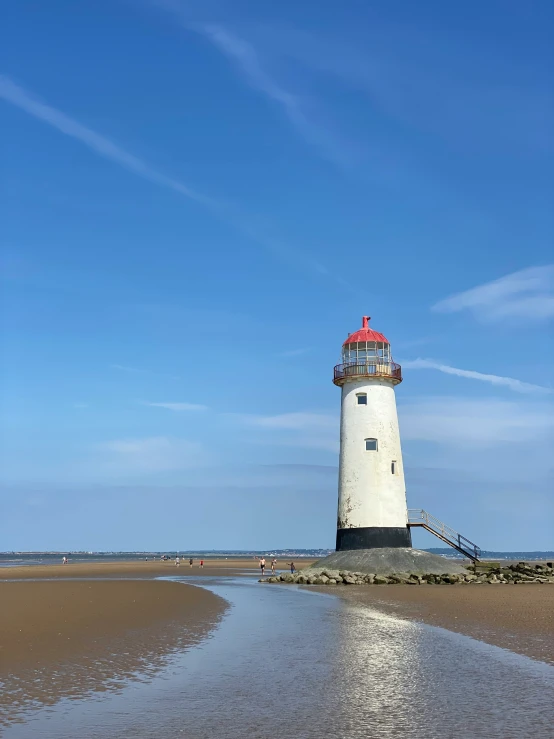 a white lighthouse on top of a sandy beach