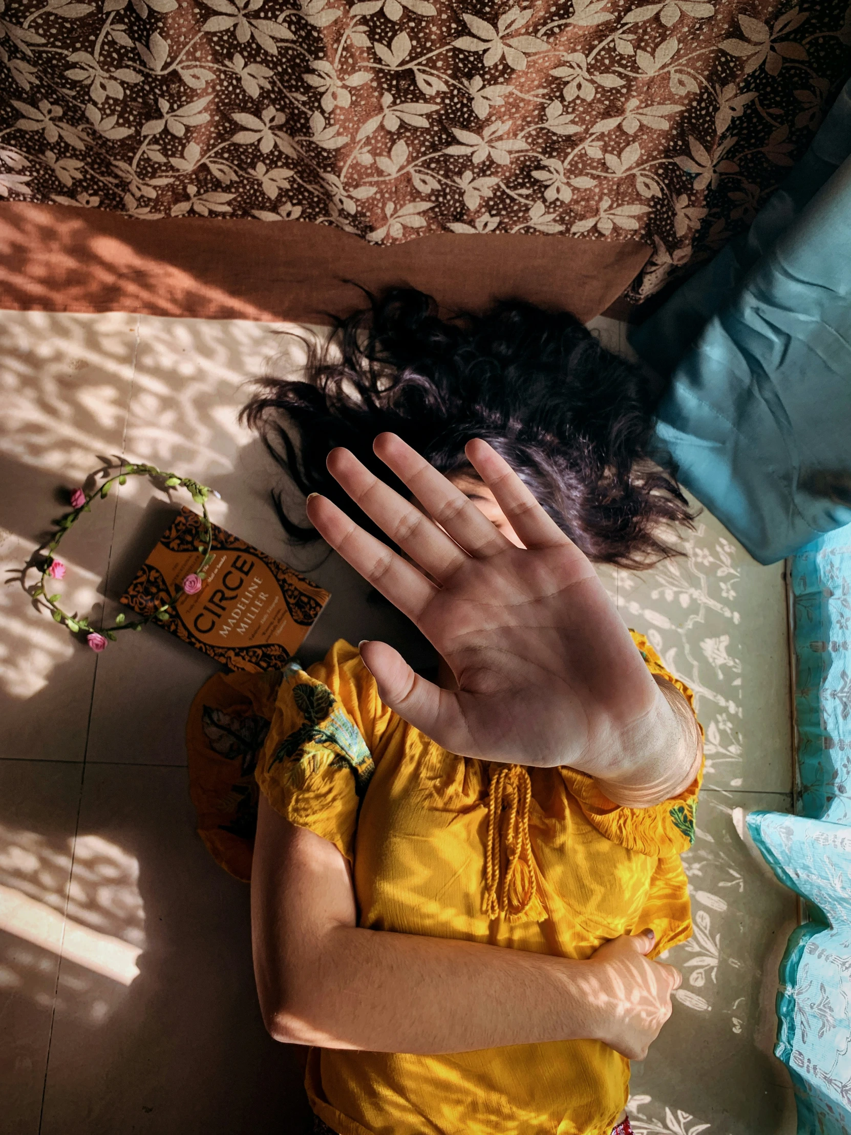 a small girl in a yellow shirt sitting on the floor