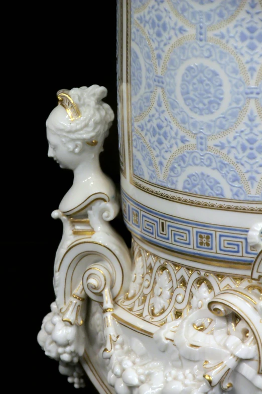 a closeup view of a white, gold and blue vase