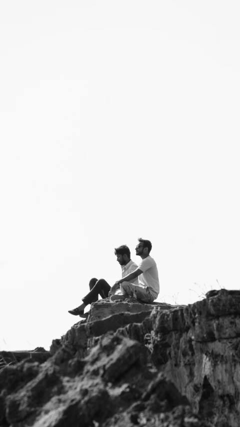 two people on top of a cliff on a sunny day