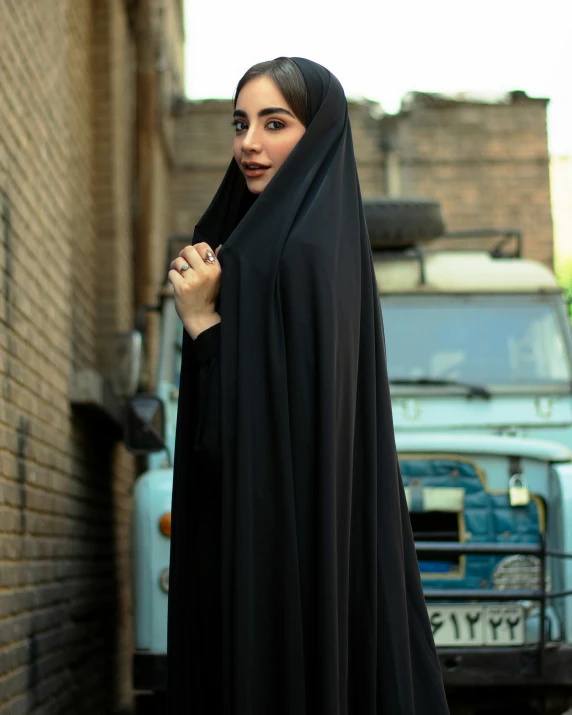 woman standing with black hijab on in the alley
