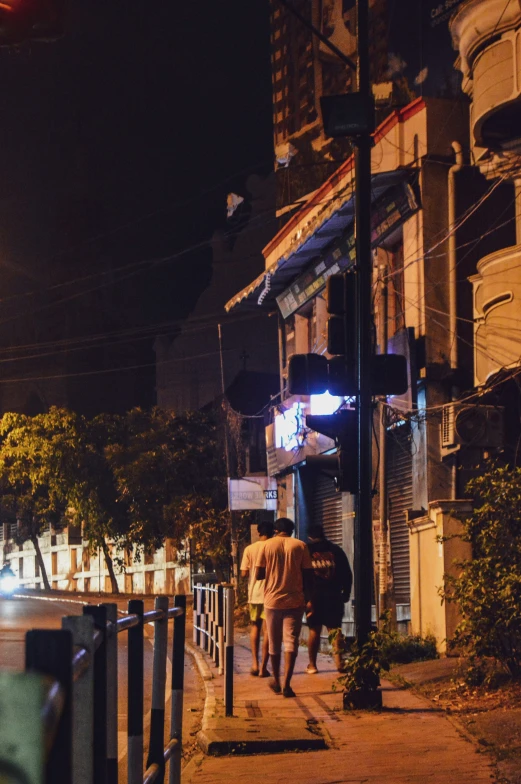 two men walk down a sidewalk at night