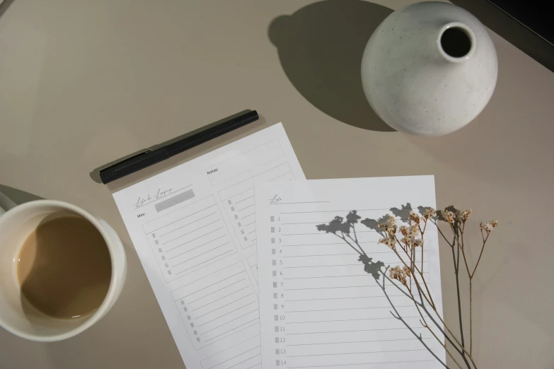 a table with two cups, pen and a vase and notes