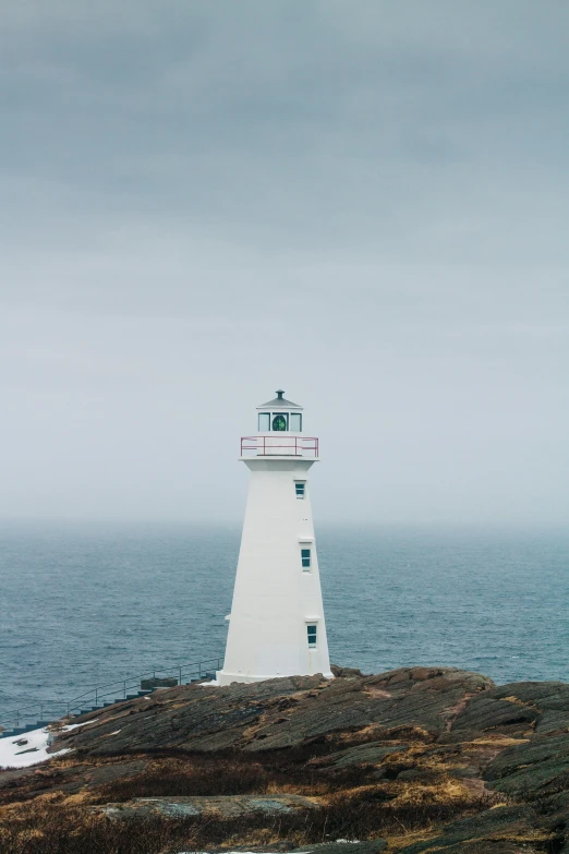 a light house sitting on top of a hill by the ocean