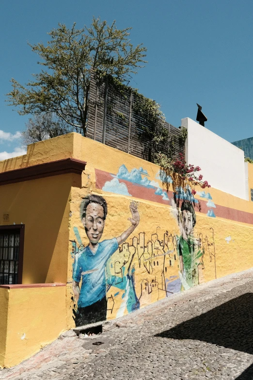 a boy wearing a blue shirt is spray painting a yellow building