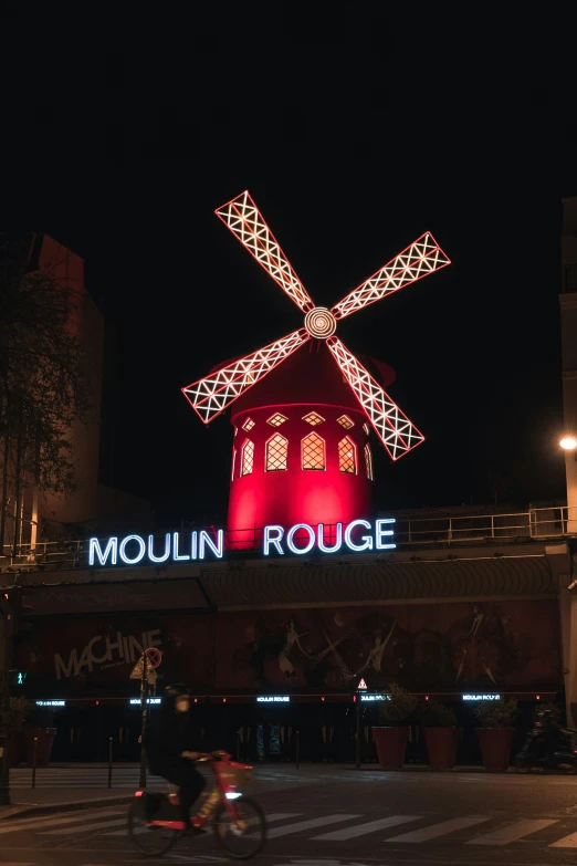 there is a large red windmill with lights all around it