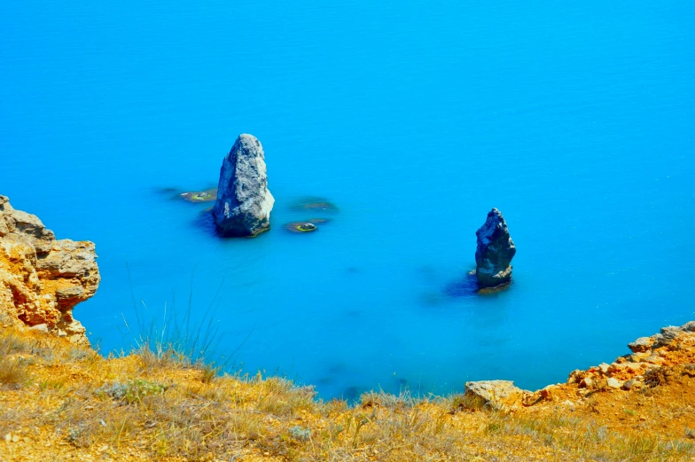 rock formations in water near rocky shore and grassy area