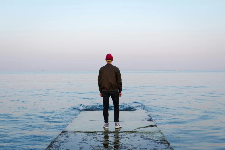 a man wearing a cap is standing on the end of a pier