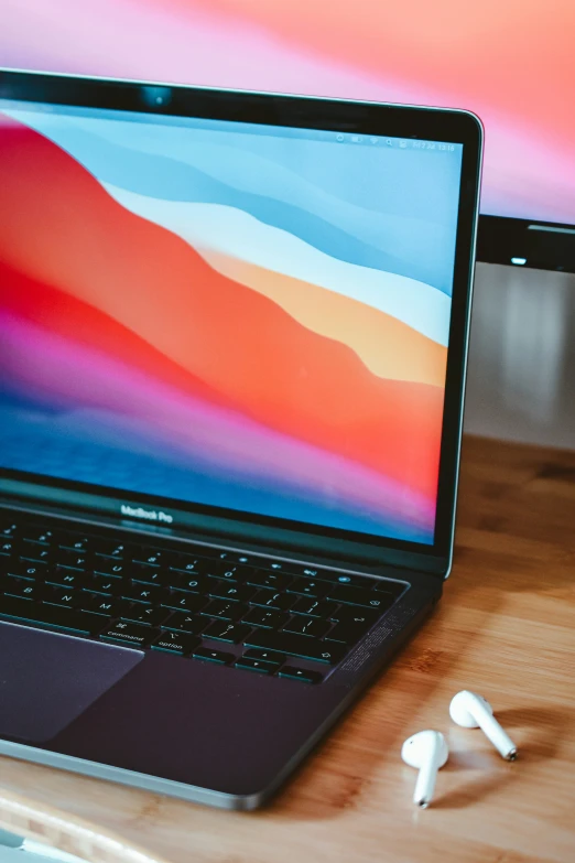 two laptops with ear buds sitting beside them on a table