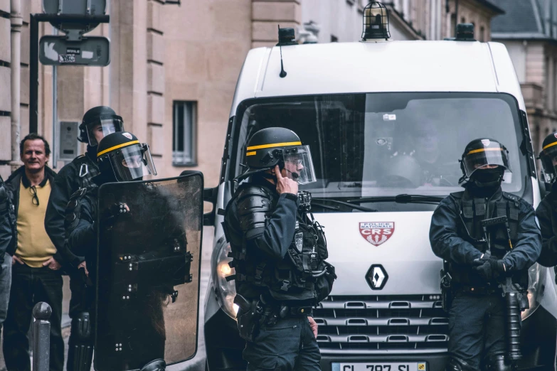 some police are standing near a white van and looking at another one