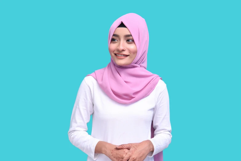 young woman standing smiling and wearing a light pink head covering