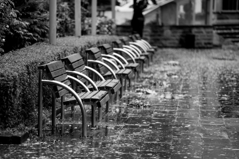 an empty bench and sidewalk in the rain
