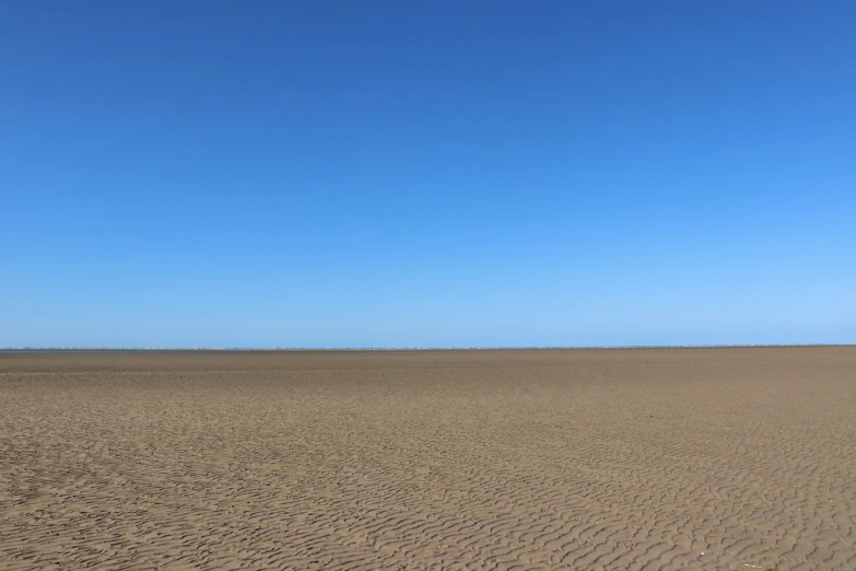 the beach has many sand dunes and an ocean in the distance