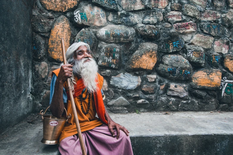 an old man with a white beard sitting in front of rocks