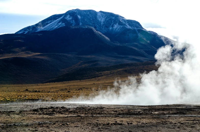 a very large steamy geyser by a big mountain