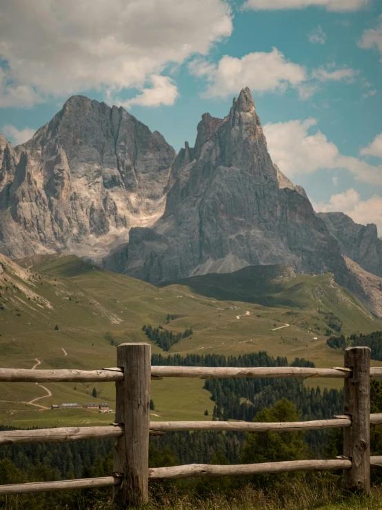 a wooden fence in front of the mountains