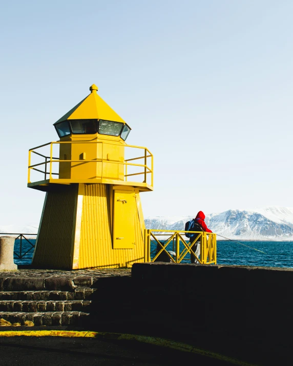 a yellow lighthouse with the water in front of it