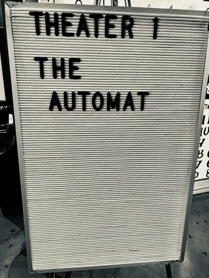 a sign that reads theater i the automat is taped into a building