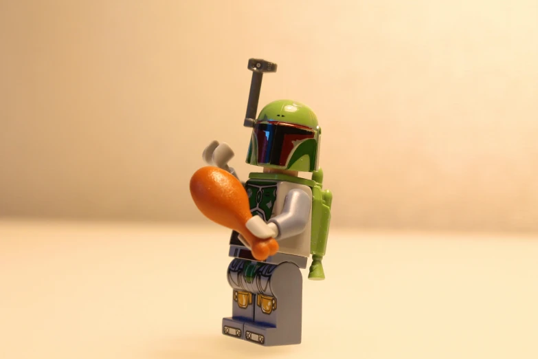 a small toy has a helmet, an orange, and a sword