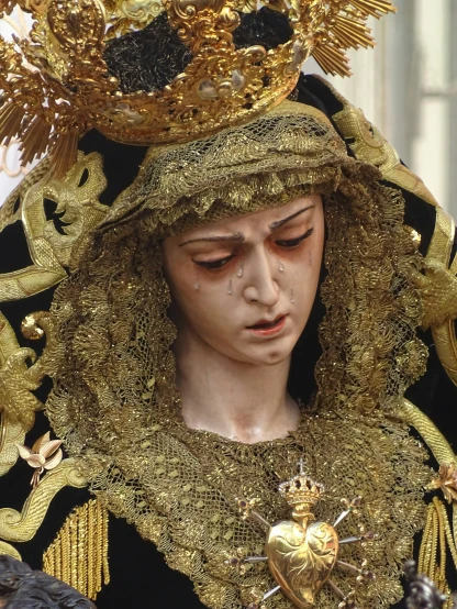 a statue wearing golden jewelry and holding a cross