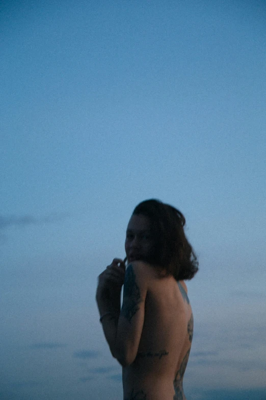 a young person with tattoos is outside by the water