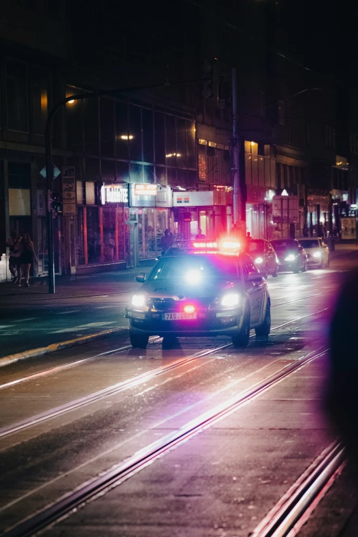 two police cars driving down a street at night