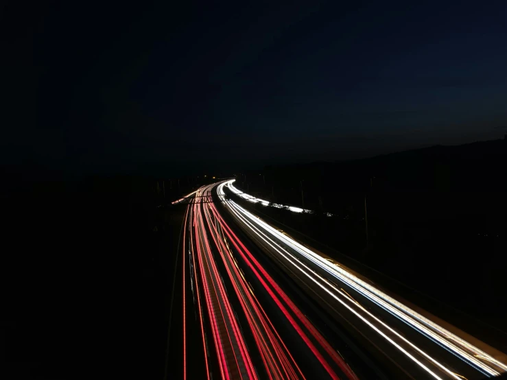 a street lined with light streaks and red and white cars