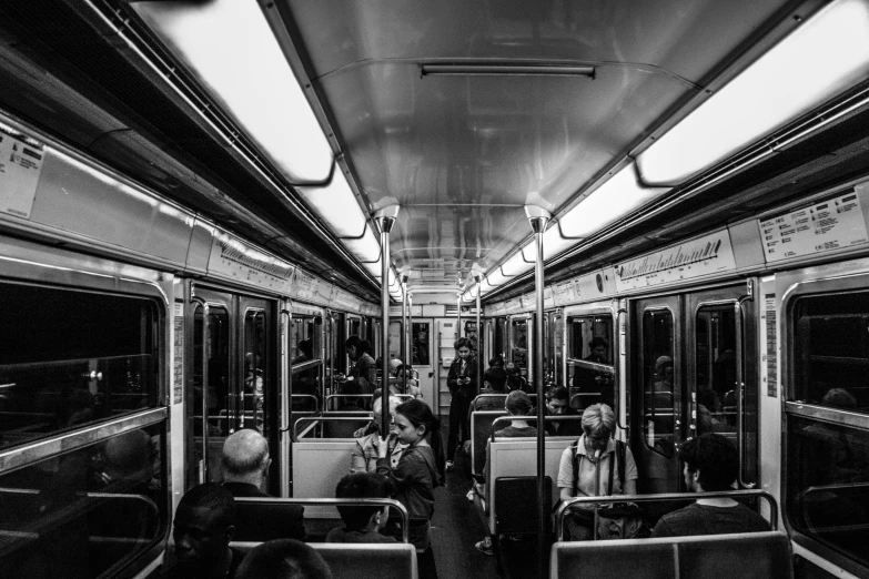 a very black and white po of people sitting on a subway car