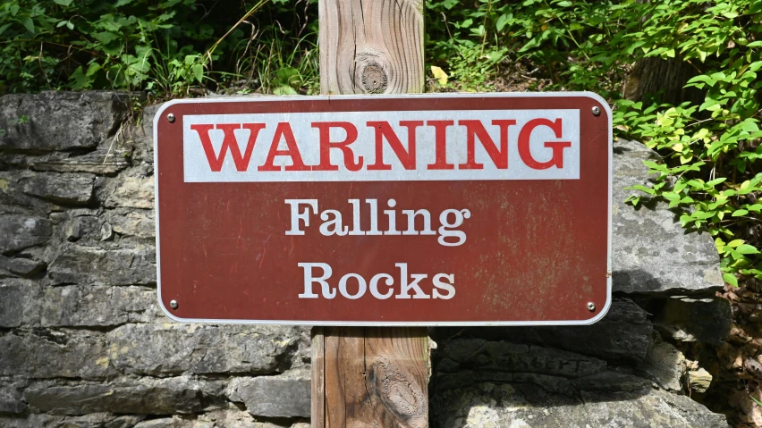 an warning sign hanging on a wood pole