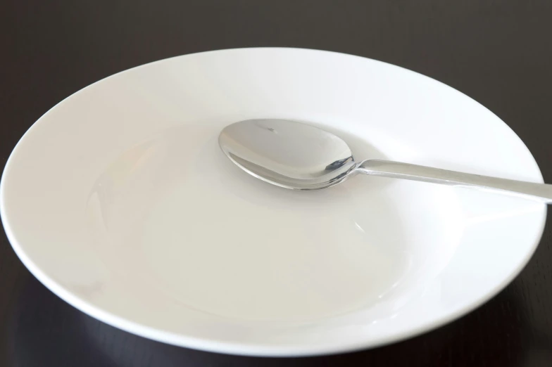 an empty white plate and spoon that is stuck into it