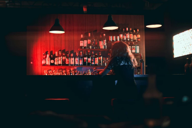 woman sitting at bar behind counter in dark room