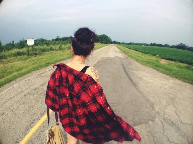 a woman is walking down an empty road