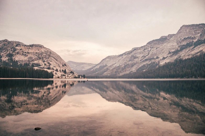 the mountains are reflected in the still water of the lake