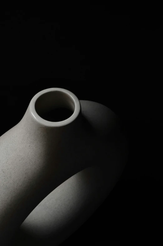 black and white po of an oval, white vase with two small holes in the base