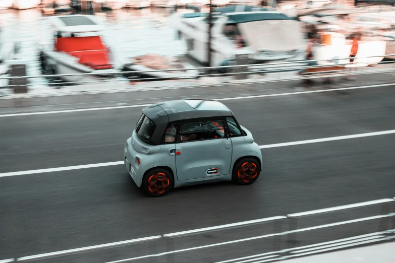 a small, light - colored car going down the road