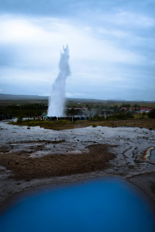 geyser in a field with people surrounding it