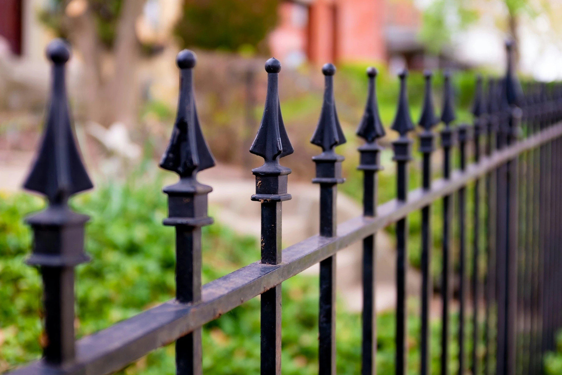 an ornate black wrought iron fence in a residential yard