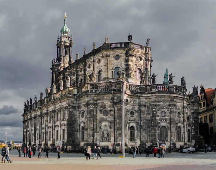 people walk around the plaza in front of an old building