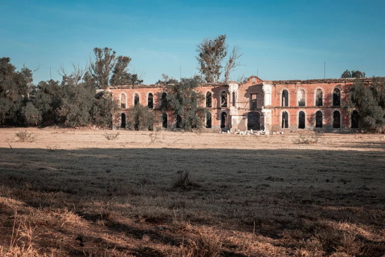 an old rundown house in a field with trees around