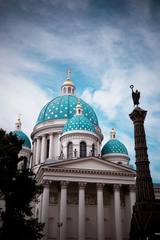 a church in the middle of the day with a blue domed roof and a column below it