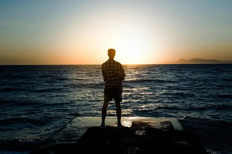 the man standing on a rock is watching the water